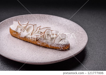Sweet eclair with custard decorated with coconut slices 121777806