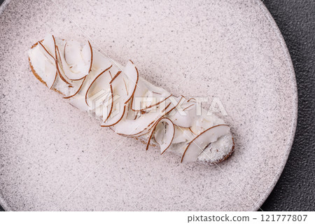 Sweet eclair with custard decorated with coconut slices 121777807
