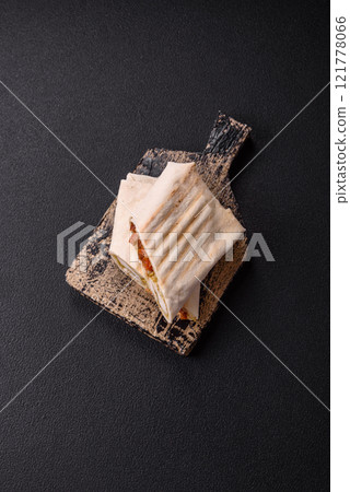 Roll with pita, meat, tomatoes, cheese, sauce, salt and spices 121778066
