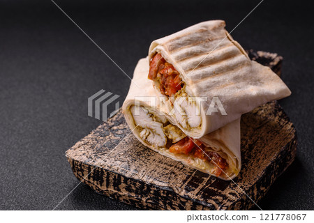 Roll with pita, meat, tomatoes, cheese, sauce, salt and spices 121778067