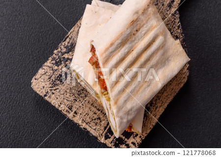 Roll with pita, meat, tomatoes, cheese, sauce, salt and spices 121778068