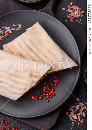 Roll with pita, meat, tomatoes, cheese, sauce, salt and spices Roll with pita, meat, tomatoes, cheese, sauce, salt and spices 121778088