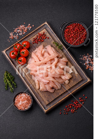 Raw chicken fillet cut into strips with spices and herbs 121778580