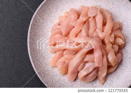 Raw chicken fillet cut into strips with spices and herbs Raw chicken fillet cut into strips with spices and herbs 121778585
