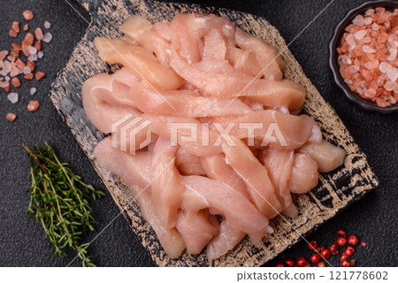 Raw chicken fillet cut into strips with spices and herbs Raw chicken fillet cut into strips with spices and herbs 121778602