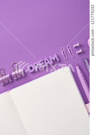 Minimalist pastel stationery flatlay with open notepad, eraser in the shape of the word Dream and stationery - pen, paper clips, clips and eraser on a lilac background. Place for your text. Minimalist pastel stationery flatlay with open notepad, eraser in the shape of the word Dream and stationery - pen, paper clips, clips and eraser on a lilac background. Place for your text. 121779282