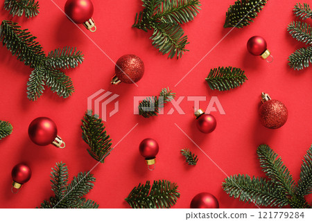 Christmas background with green pine sprigs and red Christmas baubles. Red background. 121779284