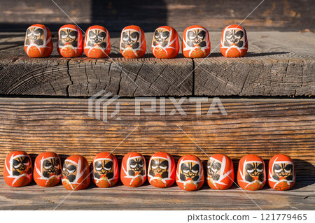 Small Daruma sitting on a bench 121779465