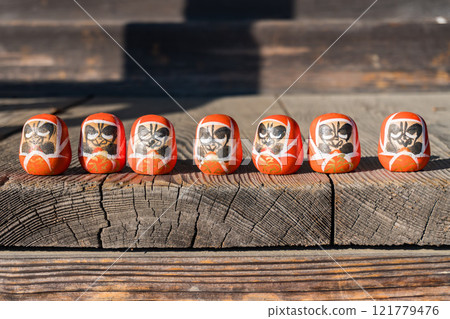 Small Daruma sitting on a bench 121779476
