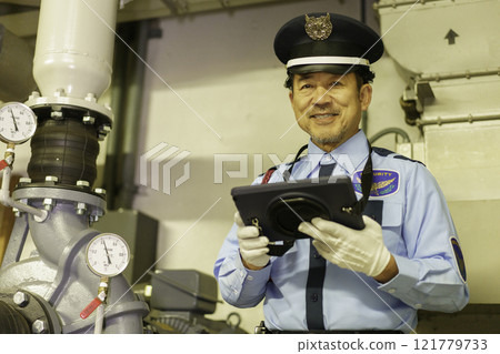 A male security guard inspecting with a tablet. Photo courtesy of Denpa Gakuen, Tokyo Electronics College. A male security guard inspecting with a tablet. Photo courtesy of Denpa Gakuen, Tokyo Electronics College. 121779733