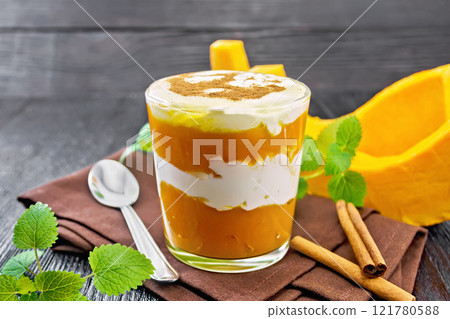 Dessert of pumpkin and yogurt in glass on dark wooden board 121780588