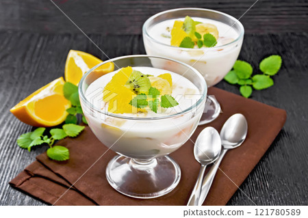 Dessert of yogurt and fruits in two glasses on black board 121780589