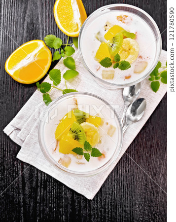 Dessert of yogurt and fruits in two glasses on wooden board top 121780590