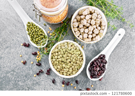 Legumes in bowls and spoons on granite top 121780600