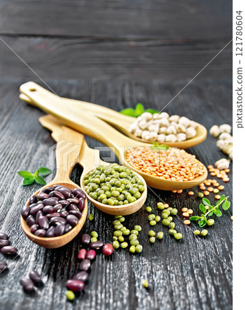 Lentils with chickpeas and beans in spoons on black board 121780604