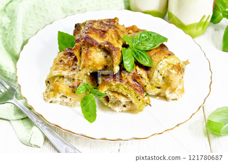 Rolls of zucchini with meat in plate on white board 121780687