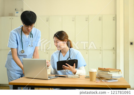 Two medical students discussing and analyzing information on a laptop in modern study area Two medical students discussing and analyzing information on a laptop in modern study area 121781091