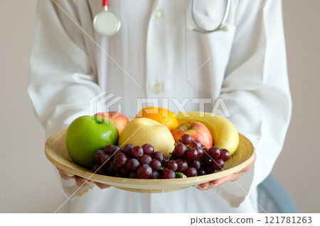 The hands of a healthy nutritionists, she holds a bowl with fruits, apples, grapes and avocados. The hands of a healthy nutritionists, she holds a bowl with fruits, apples, grapes and avocados. 121781263