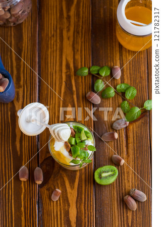 homemade yogurt with kiwi, honey and nuts in a glass on a wooden table homemade yogurt with kiwi, honey and nuts in a glass on a wooden table 121782317
