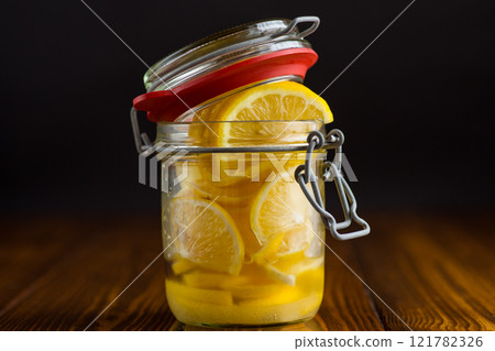 sliced lemons in sugar syrup in a glass jar, canned 121782326