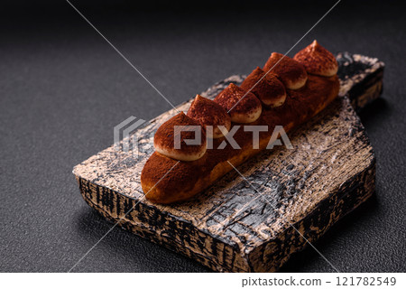 Sweet eclair with chocolate custard sprinkled with cocoa powder Sweet eclair with chocolate custard sprinkled with cocoa powder 121782549