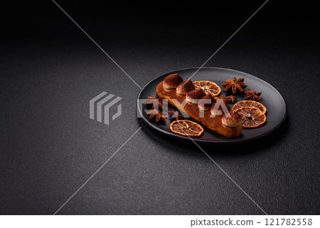 Sweet eclair with chocolate custard sprinkled with cocoa powder 121782558