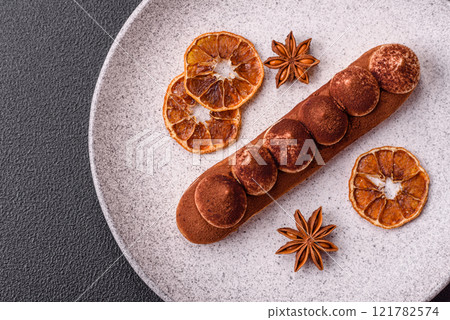 Sweet eclair with chocolate custard sprinkled with cocoa powder 121782574