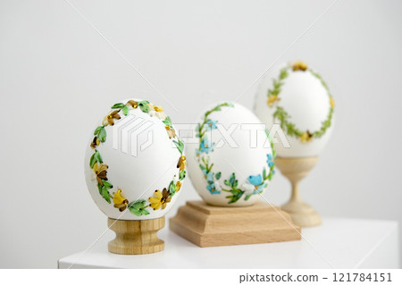 A row of decorated eggs are displayed on a shelf. The eggs are of various sizes and colors, and they are arranged in a neat row A row of decorated eggs are displayed on a shelf. The eggs are of various sizes and colors, and they are arranged in a neat row 121784151