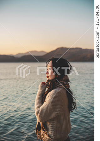 晚上的湖和穿著針織衫和圍巾的年輕女子 晚上的湖和穿著針織衫和圍巾的年輕女子 121784306