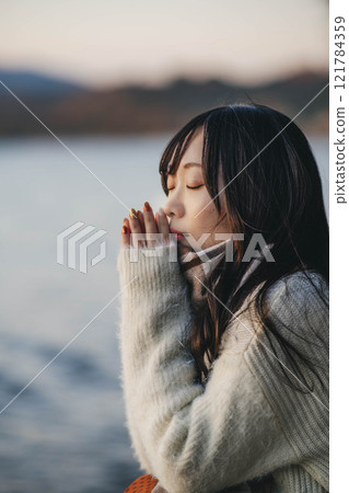 Evening lake and a young woman in a knitted sweater and scarf 121784359