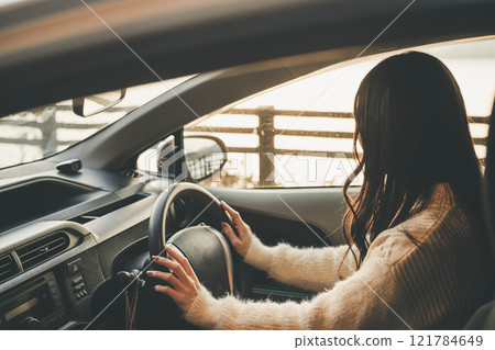 A young woman with long hair driving a car 121784649