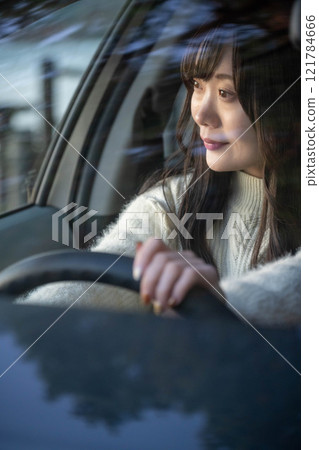 A young woman with long hair driving a car 121784666