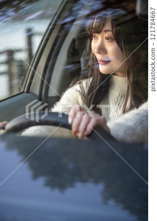 A young woman with long hair driving a car 121784667