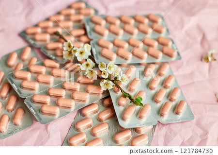 Overhead View of Multiple Blister Packs of Medication on a Crumpled Pink Surface 121784730