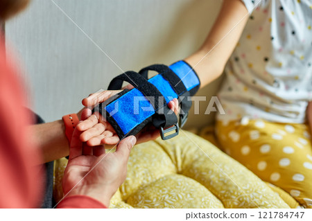 Physical Therapist Fitting a Support Brace on a Young Girls Arm 121784747