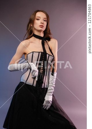 Elegant woman in corset and gloves poses stylishly for modern fashion shoot 121784863