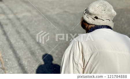 Rear view and shadow of an elderly woman walking on the road Rear view and shadow of an elderly woman walking on the road 121784888