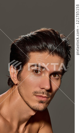 Close-up side profile of man with calm and confident expression. His smooth skin and sharp jawline highlighted against dark background. Close-up side profile of man with calm and confident expression. His smooth skin and sharp jawline highlighted against dark background. 121785158