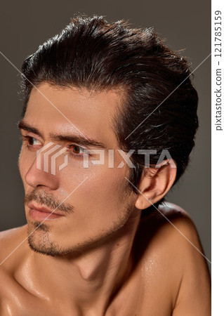 Close-up side profile of man with serene expression. His smooth skin and sharp jawline highlighted against dark background. Close-up side profile of man with serene expression. His smooth skin and sharp jawline highlighted against dark background. 121785159