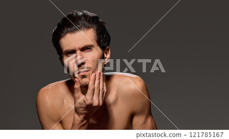 Close-up of man with questioning expression. His slightly tilted head and bare shoulders highlight his sharp features. 121785167