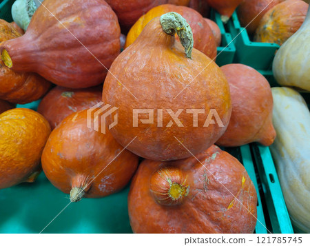 Small orange pumpkins are in a green container on a shelf in the store. Small orange pumpkins are in a green container on a shelf in the store. 121785745