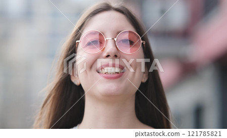 Happy woman in pink sunglasses outdoors smiling Happy woman in pink sunglasses outdoors smiling 121785821