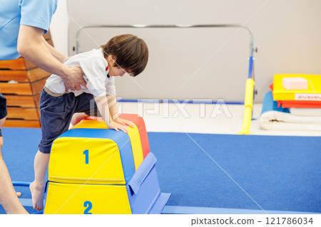 A boy practicing vaulting in a gymnastics class 121786034
