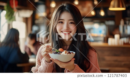 Beautiful woman eating an acai bowl 121787403