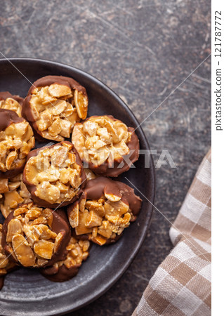 Photography of chocolate Florentines cookies with almonds and chocolate on plate on black table. Top view. Photography of chocolate Florentines cookies with almonds and chocolate on plate on black table. Top view. 121787772