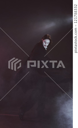 Man with pale face and cape, looks as vampire, spins dramatically, shows terrifying sharp fangs, in dimly lit setting. 121788332