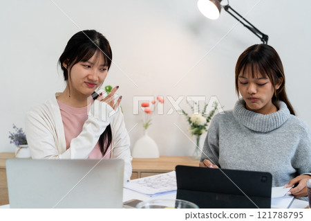 Female higher education student using laptop and studying book in home, Online learning. Female higher education student using laptop and studying book in home, Online learning. 121788795
