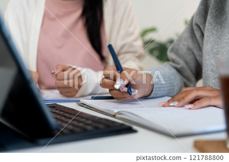 Female higher education student using laptop and studying book in home, Online learning. Female higher education student using laptop and studying book in home, Online learning. 121788800