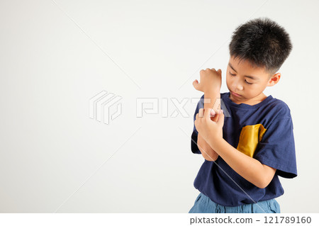 Asian little kid boy scratching itchy arm from a mosquito bite at studio shot isolated on white background, Portrait of Thai primary child dermatitis and scabies, Allergy symptoms, Malaria day concept 121789160
