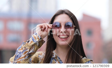 Happy woman in pink sunglasses outdoors smiling 121790309